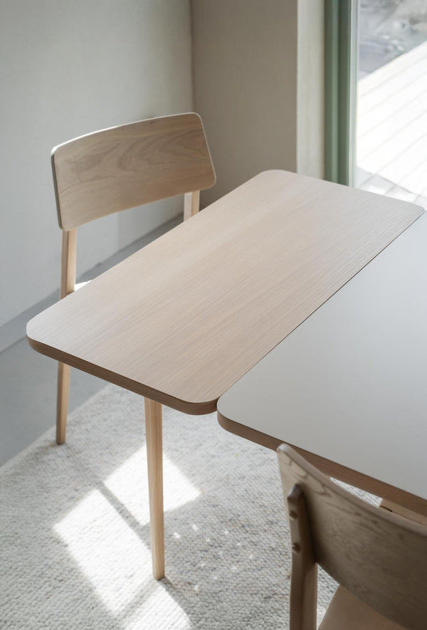 Ljust träbord med matchande stol i minimalistisk skandinavisk design vid fönster