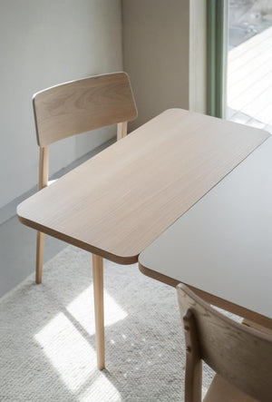 Ljust träbord med matchande stol i minimalistisk skandinavisk design vid fönster