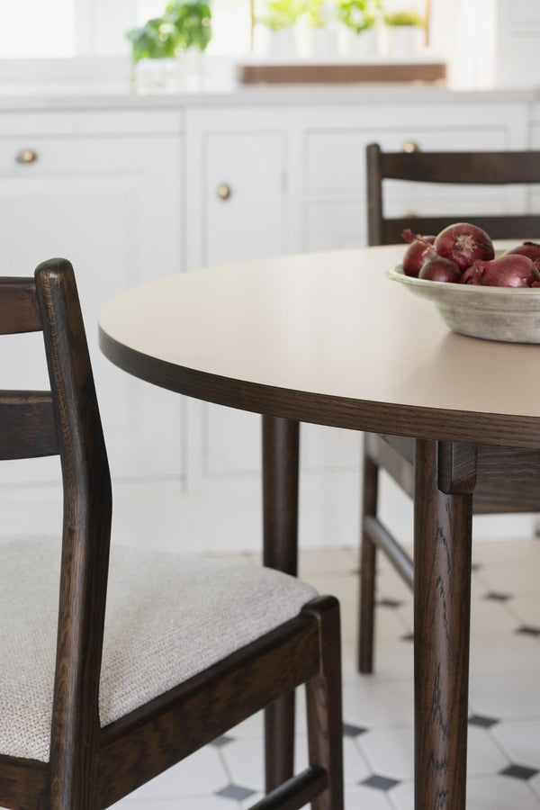 Runt matbord i vit laminat med mörkbrun träkant och matchande stolar med ljusgrå sits