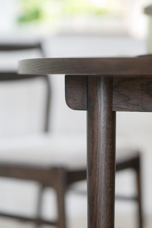 Närbild på mörkbrun träbordskant med synlig detaljerad fogkonstruktion och cylindrisk bordsstolpe