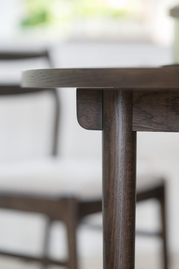 Närbild på mörkbrun träbordskant med synlig detaljerad fogkonstruktion och cylindrisk bordsstolpe