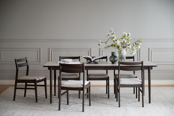 Matgrupp med mörkt träbord och sex stolar med grå dynor i elegant matsal med vit lambrisering