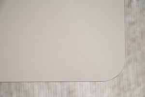 Vit eller ljusgrå bordsskiva med rundad hörna mot ljus träbakgrund