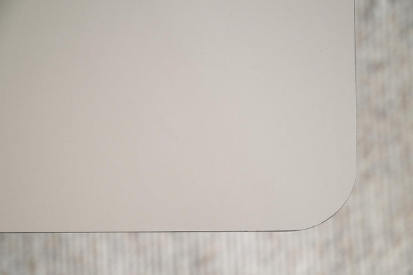 Vit eller ljusgrå bordsskiva med rundad hörna mot ljus träbakgrund