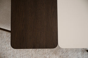 Närbilder av bord med mörk ekfanér och ljust laminat samt ljusgrå textilmatta