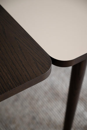 Närbild på mörkbrun träbordskiva med rundade hörn och träben, visar detaljerad trästruktur och finish