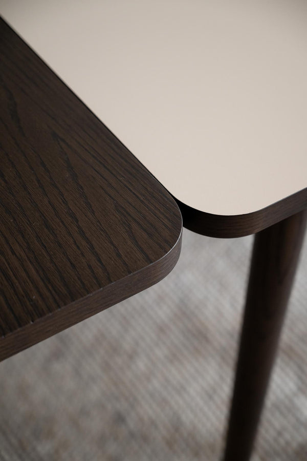 Närbild på mörkbrun träbordskiva med rundade hörn och träben, visar detaljerad trästruktur och finish