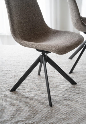 Grå matstol med tygsits och svarta metallben i modern skandinavisk design på ljus matta