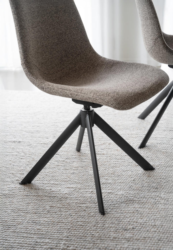 Grå matstol med tygsits och svarta metallben i modern skandinavisk design på ljus matta