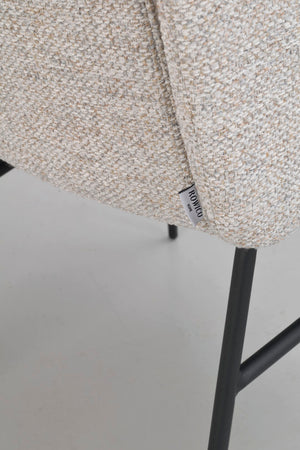 Närbild av beige stol med bouclétyg och svarta metallben, visar tygets struktur och Rowico-etikett