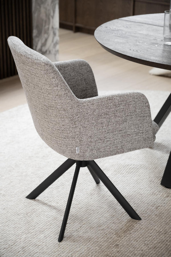 Grå matstol med armstöd och svart snurrfot i modern design vid runt marmorbord