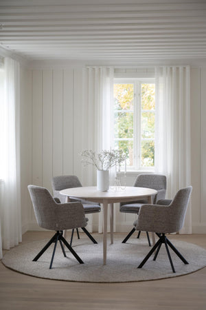 Rund matbord i vitt med grå stolar och svarta ben i ljust skandinaviskt matrum