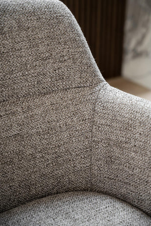 Närbild på grå textilklädsel på fåtölj med tydlig vävstruktur och mjuka kurvor