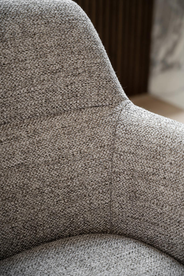 Närbild på grå textilklädsel på fåtölj med tydlig vävstruktur och mjuka kurvor