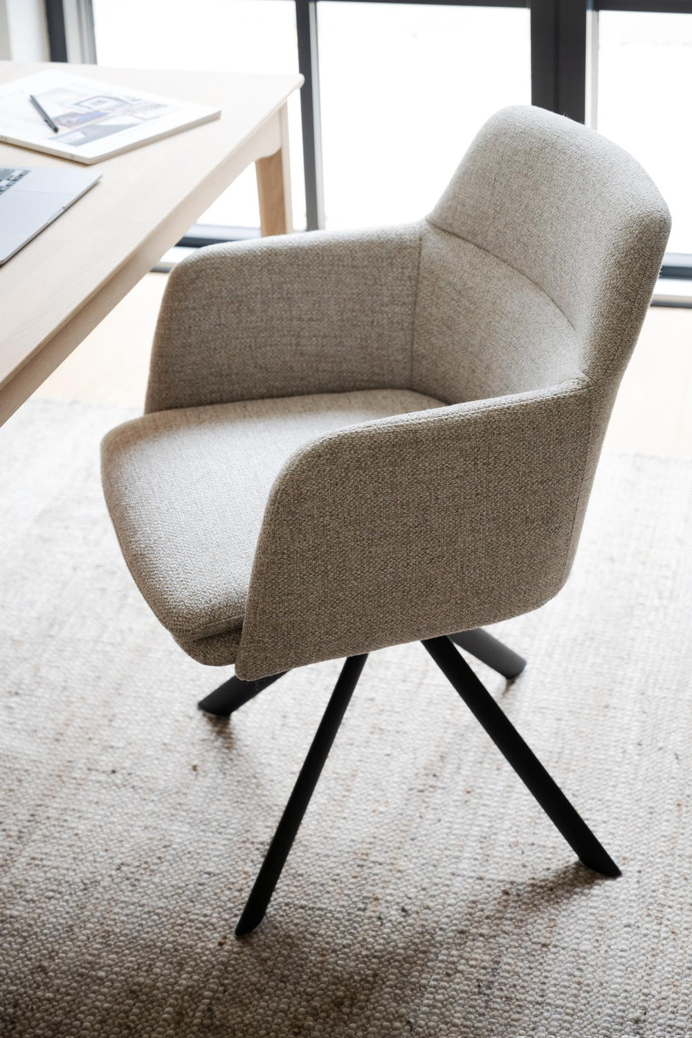 Beige stoppad matstol med svart snurrbart underrede i metall, modern design med armstöd