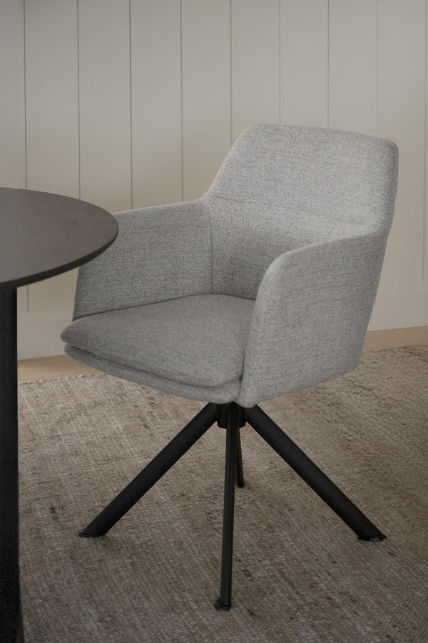 Grå snurrbar fåtölj med armstöd och svarta ben i modern design bredvid runt bord