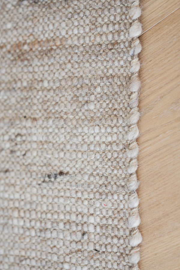 Närbild av beige matta med strukturerad yta mot ljust trägolv