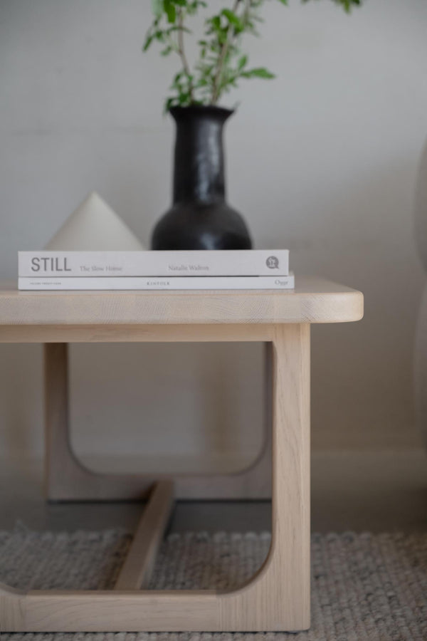 Ljust träsoffbord i ek med böcker och svart vas, skandinavisk minimalistisk design för vardagsrum