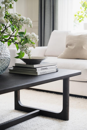 Soffbord i mörkt trä med böcker och vita blommor i modern vardagsrumsinredning