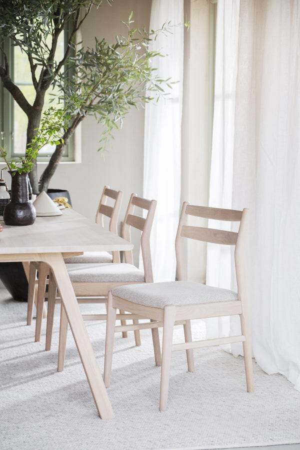 Ljusa trämatgrupp med stoppad sits i skandinavisk stil vid fönster med gröna växter