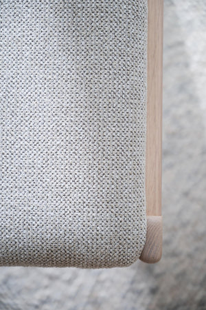 Närbild på grå stickad textil med träben från fåtölj eller stol