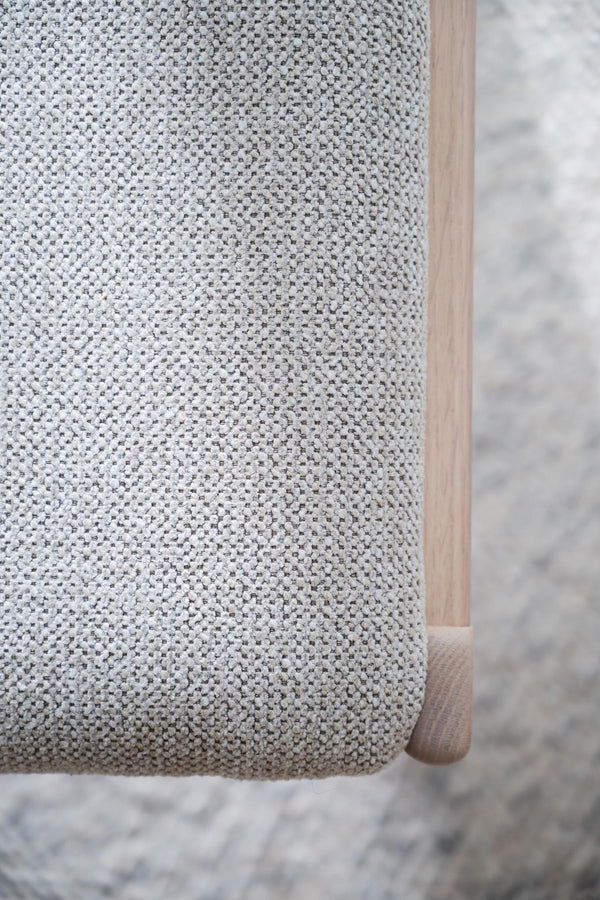 Närbild på grå stickad textil med träben från fåtölj eller stol