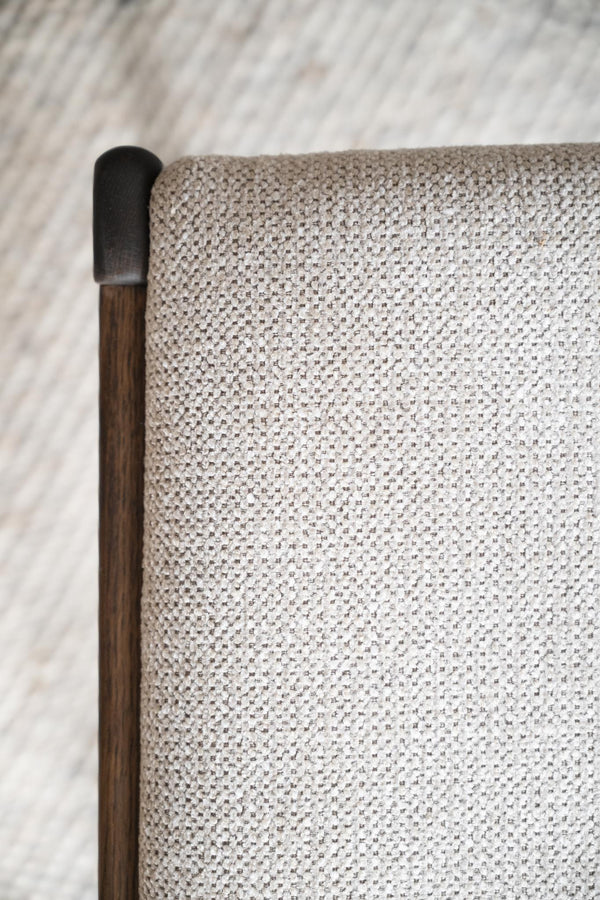 Närbild på trähandtag med svart topp mot ljus stickad textil i beige och vitt mönster