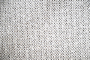 Vit stickad tygyta med fint mönster, närbild av textil struktur och material