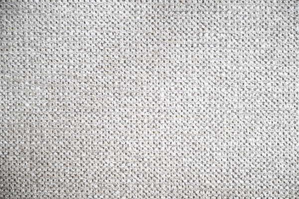 Vit stickad tygyta med fint mönster, närbild av textil struktur och material