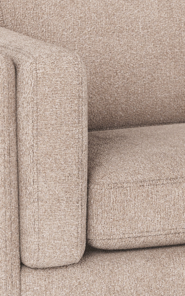 Beige soffa i närbild med mjuk klädsel och rundad armstöd