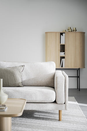 Ljusgrå tvåsitssoffa med träben och dekorativ kudde i skandinavisk vardagsrumsmiljö med träskåp