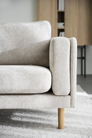 Beige soffa med träben och mjuk klädsel i vardagsrum med neutral inredning