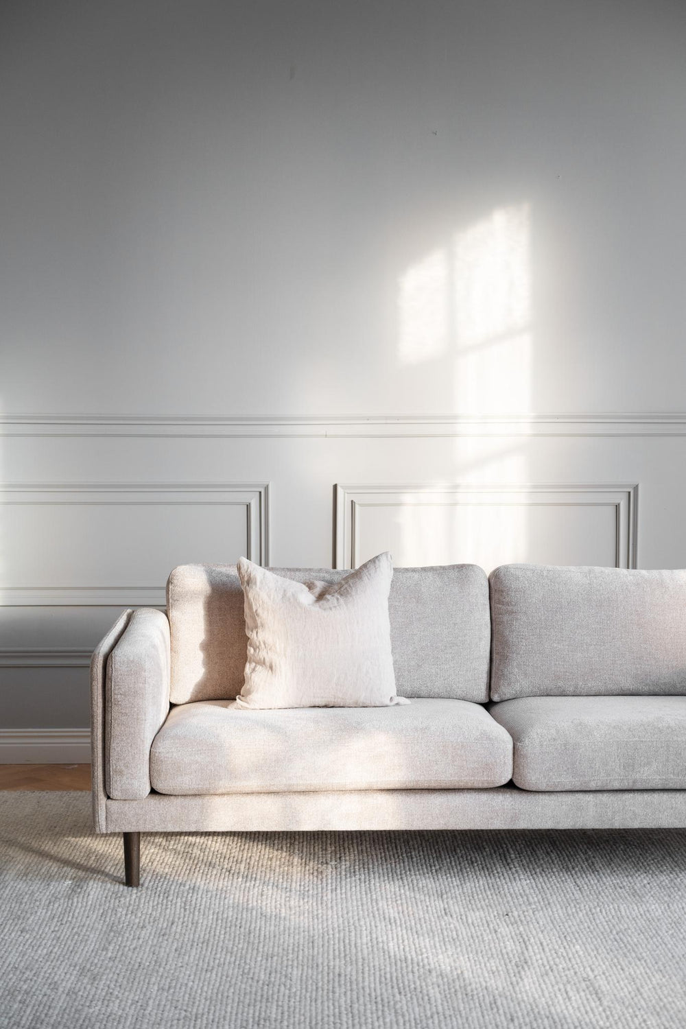 Beige tvåsits soffa med träben i modern skandinavisk design på vit bakgrund