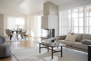 Modernt vardagsrum med grå soffa, soffbord och öppen spis med matplats i bakgrunden