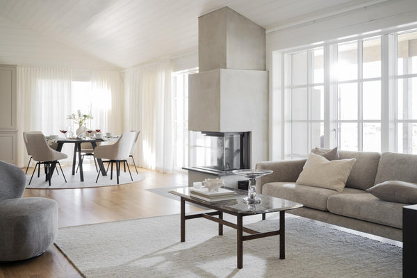 Modernt vardagsrum med grå soffa, soffbord och öppen spis med matplats i bakgrunden