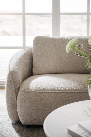 Beige bouclé fåtölj med mjuka rundade former vid fönster i ljust vardagsrum
