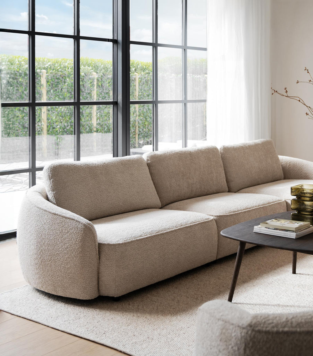 Beige tresitsssoffa med rundade former och tre separata sittdynor mot vit bakgrund