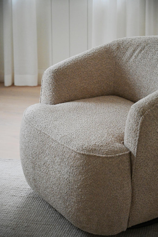 Beige bouclé fåtölj med rundad organisk form och mjuk teddy-textil i ljust rum