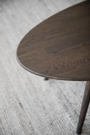 Rund träbordsskiva i mörkt trä med synlig årsringsstruktur och dekorativ kant, stående på matta