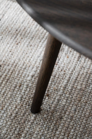 Mörkbrunt träben på möbel mot ljus melerad matta i närbild