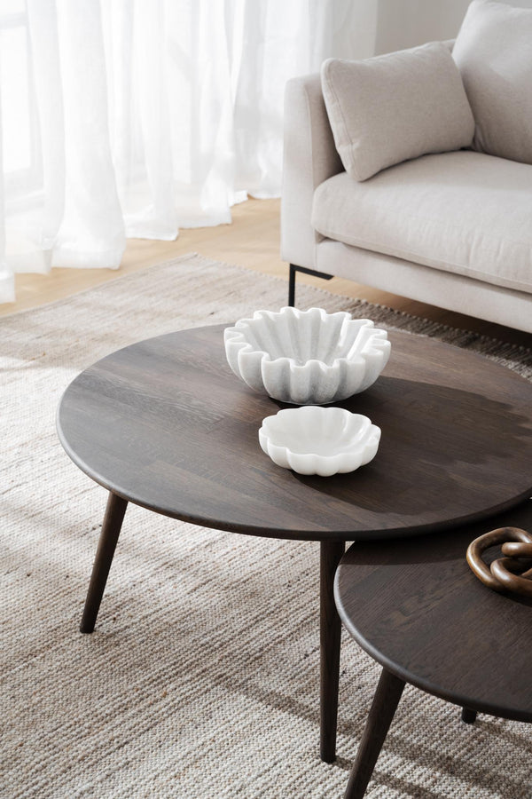 Runda soffbord i mörkt trä med vita dekorativa skålar i vardagsrum med beige soffa