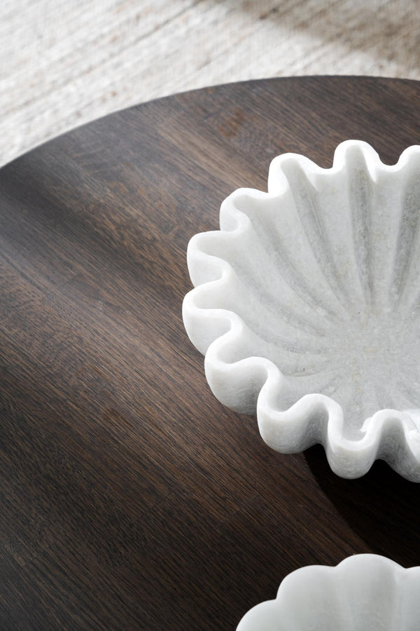 Vit dekorativ vas med vågformad kant i marmor på mörkt träbord