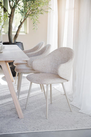 Grå stoppad matstol med böjda armstöd och ljusa ben vid matbord i modern skandinavisk stil