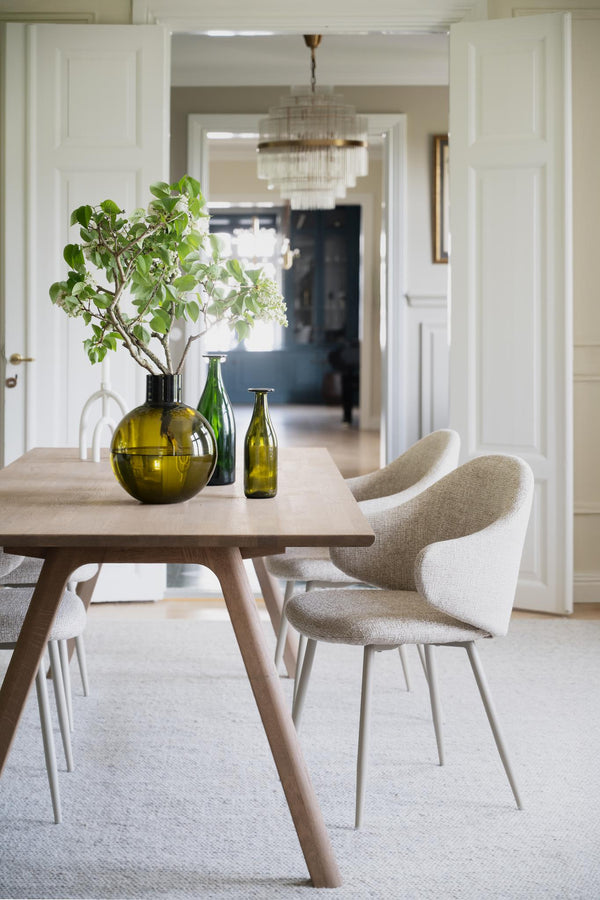 Matgrupp med ljust trä och beige stolar i skandinavisk stil med gröna glasvaser som dekoration