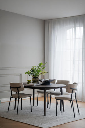 Matgrupp med runt svart bord och fyra beige stolar i minimalistisk matsal med vita gardiner