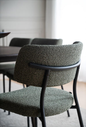 Matstol med grön boucléklädsel och svart träram vid matbord i modern skandinavisk matsal