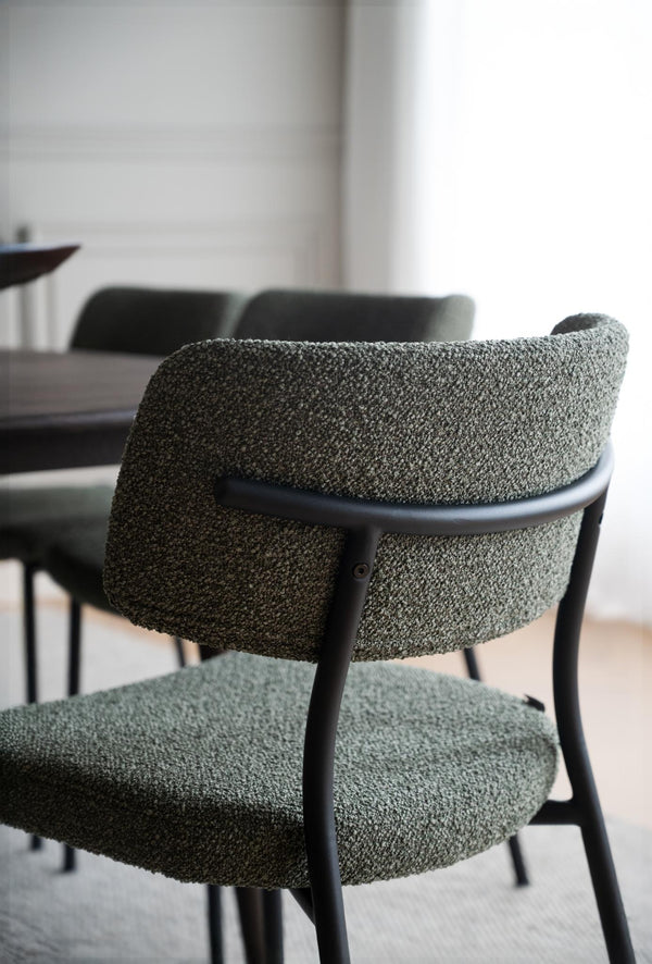 Matstol med grön boucléklädsel och svart träram vid matbord i modern skandinavisk matsal