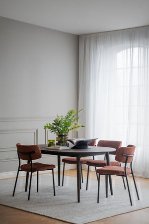 Matgrupp med runt svart bord och fyra rosa stolar i modern matsal med vita väggar och gardiner