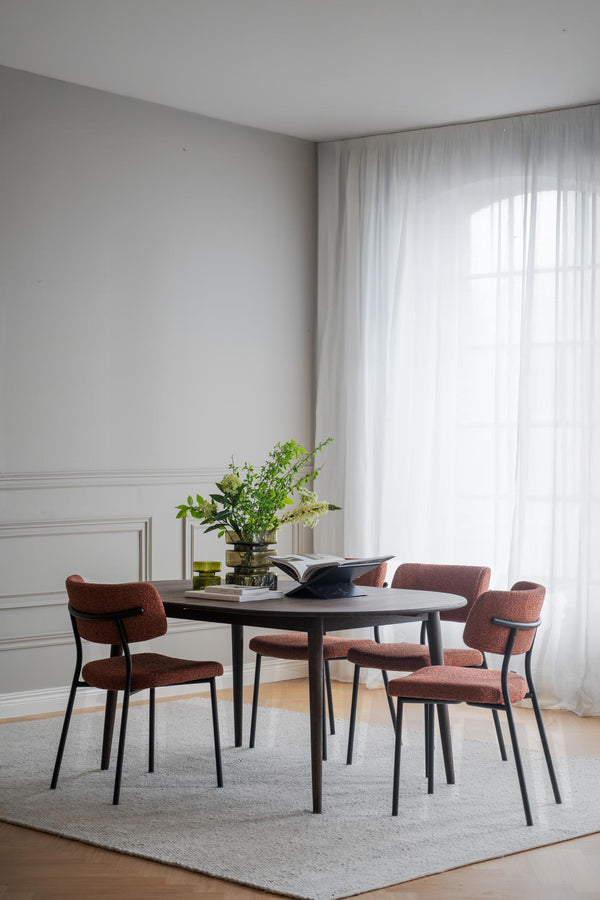 Matgrupp med runt svart bord och fyra rosa stolar i modern matsal med vita väggar och gardiner