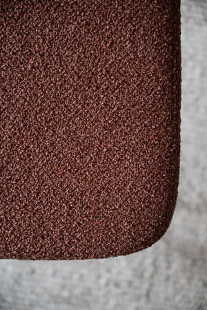 Närbild på rödbrunt bouclé-tyg med texturerad yta och mjuk struktur
